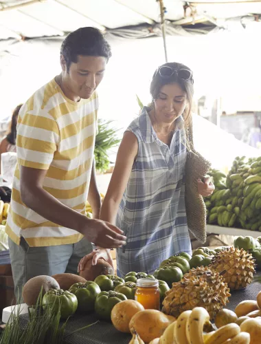 Hilo Farmers Market Couple browsing fresh fruits and vegetables at an outdoor farmers market in Hilo.