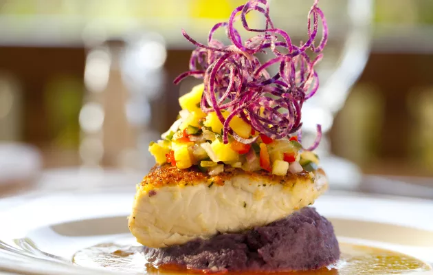 Artistically plated dish featuring colorful vegetables and fish